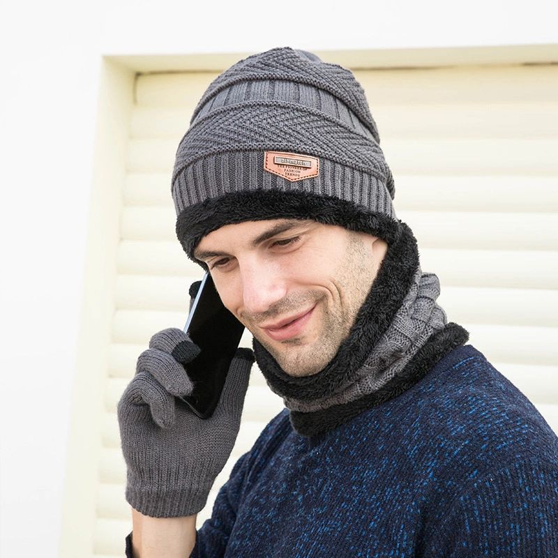 A man wearing gloves and a hat talking on the phone.