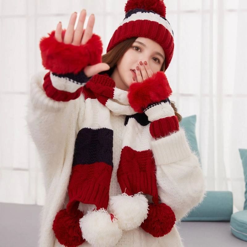 A girl wearing a red and white hat, scarf and gloves.